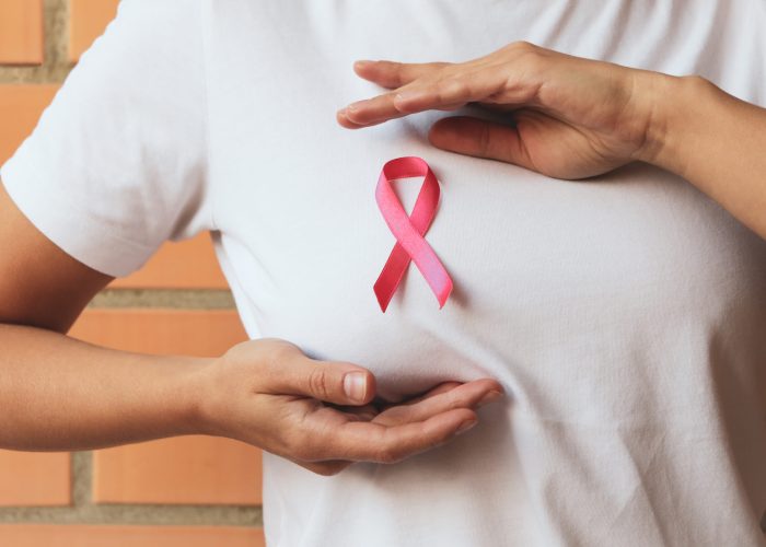 Woman with pink awareness ribbon against brick wall background